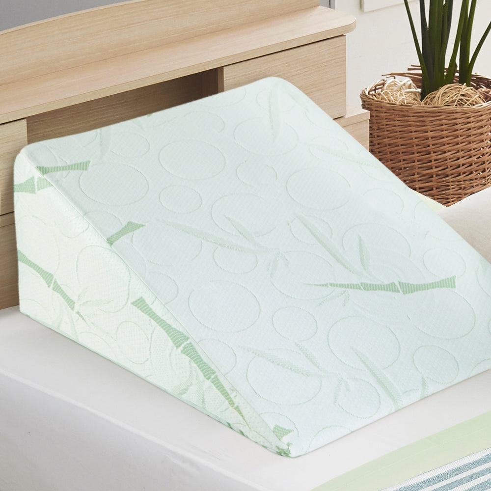 Green wedge bamboo  pillow on a bed with a wooden headboard 